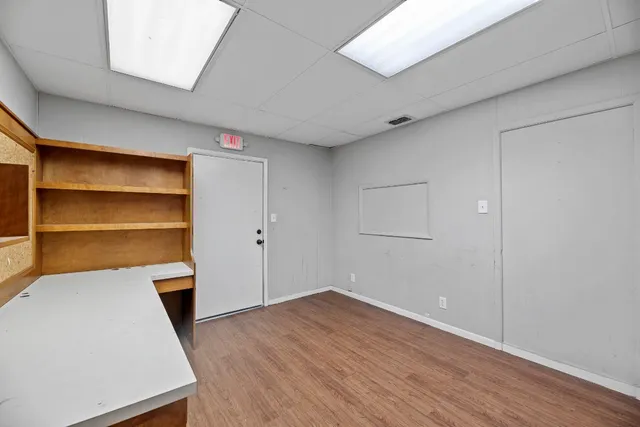 a view of an empty room with a fireplace and wooden floor