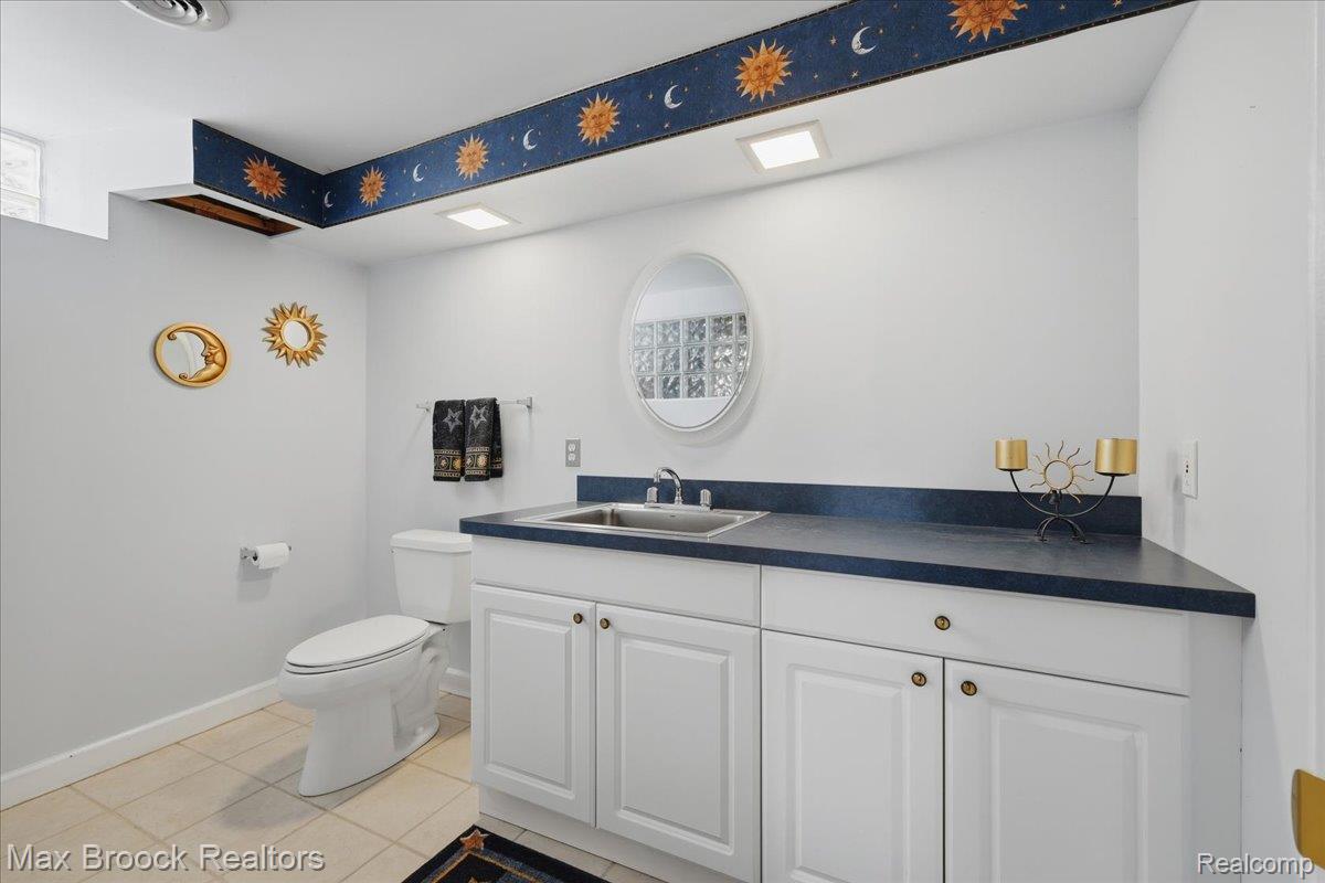 1731 Rico Road Commerce Township, MI 48382 - Photo 41 of 48 White vanity with gold-tone hardware, dark countertop, and integrated sink