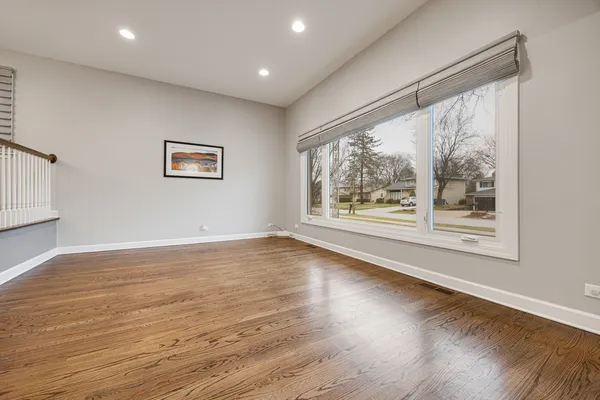 a view of an empty room with wooden floor and windows