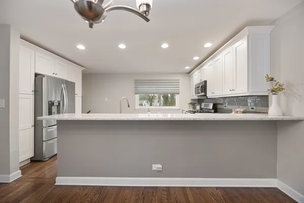 a kitchen with stainless steel appliances granite countertop a stove top oven a sink and white cabinets