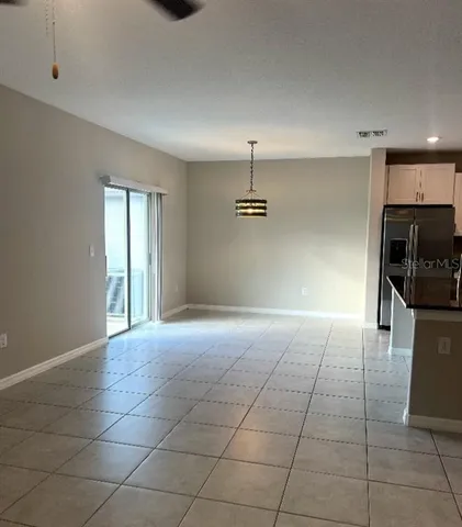 a view of an empty room with a chandelier fan