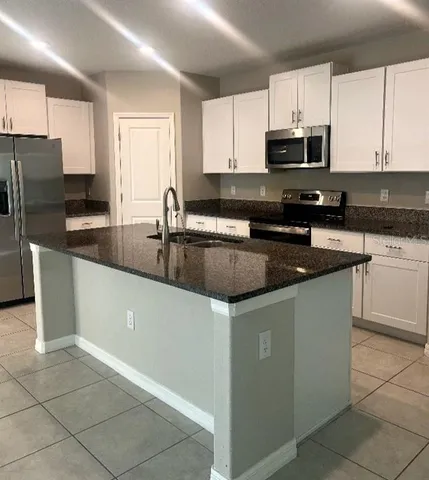 a kitchen with granite countertop a sink cabinets and stainless steel appliances