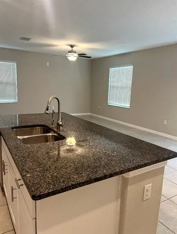 an empty room with windows and ceiling fan