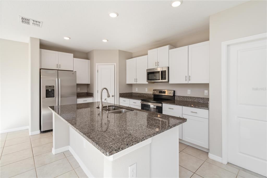 1777 Fred Ives Street Ruskin, FL 33570 - Photo 10 of 35 a kitchen with kitchen island granite countertop a sink a stove a refrigerator a counter top space and cabinets
