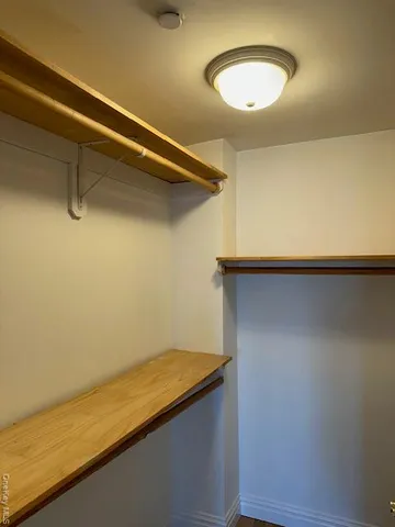 a view of a room with a hanging light and hardwood floor
