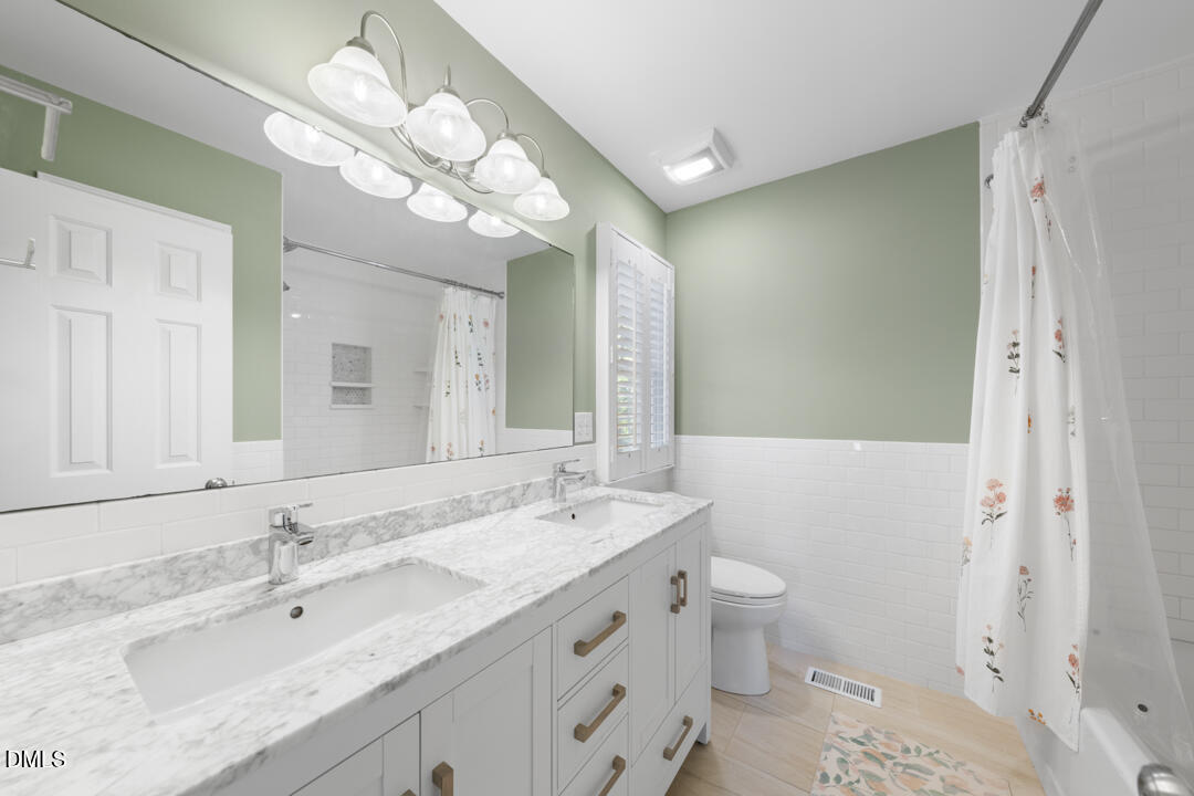 405 Latta Road Durham, NC 27712 - Photo 22 of 43 a bathroom with a granite countertop sink a toilet and a large mirror