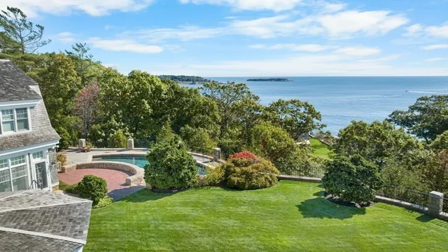 a view of a white house with large windows and flower plants