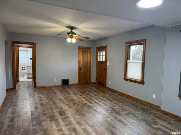 an empty room with windows and fan