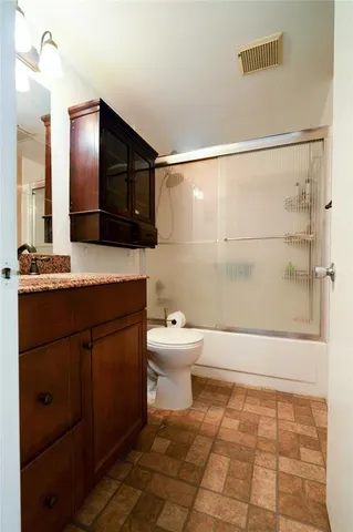 a bathroom with a granite countertop sink and a toilet