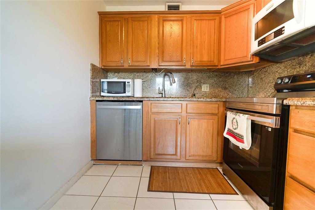 300 Southwest 134th Way, Unit 402E Pembroke Pines, FL 33027 - Photo 8 of 46 a kitchen with granite countertop a stove top oven cabinets and a microwave