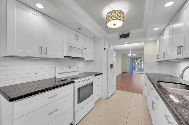 a kitchen with granite countertop a stove sink and cabinets