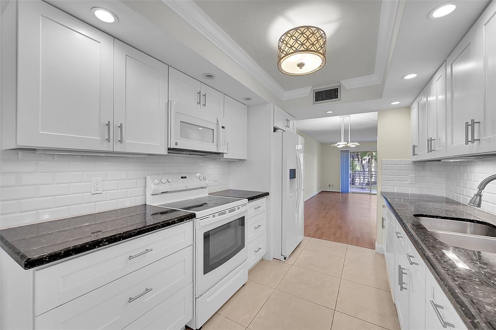 a kitchen with granite countertop a stove sink and cabinets