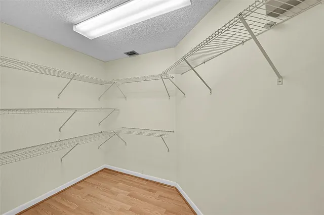 an empty room with wooden floor ceiling fan and window