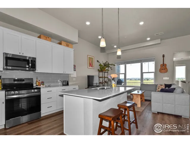 a kitchen with stainless steel appliances kitchen island granite countertop a stove a sink dishwasher and a microwave with wooden floor