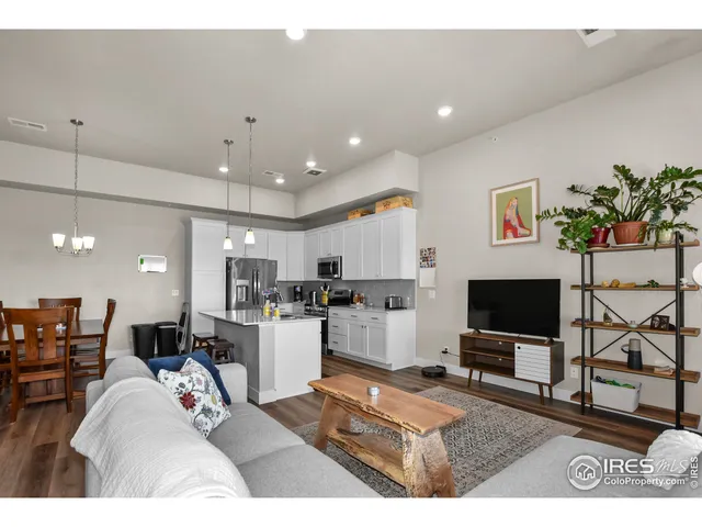 a living room with stainless steel appliances furniture and a flat screen tv