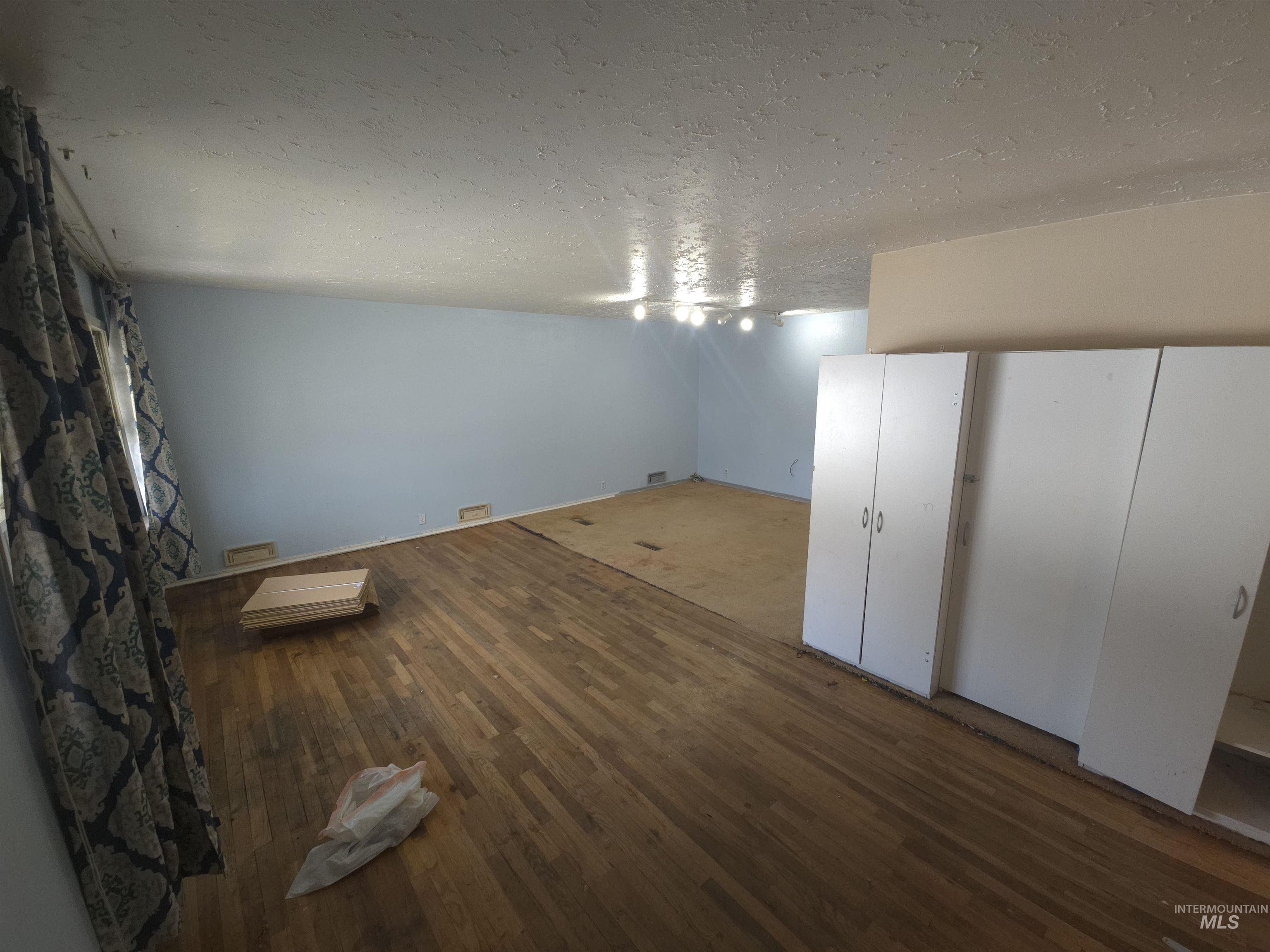 458 Rose Street North Twin Falls, ID 83301 - Photo 3 of 17 Unfurnished dining area with a textured ceiling and dark wood-type flooring