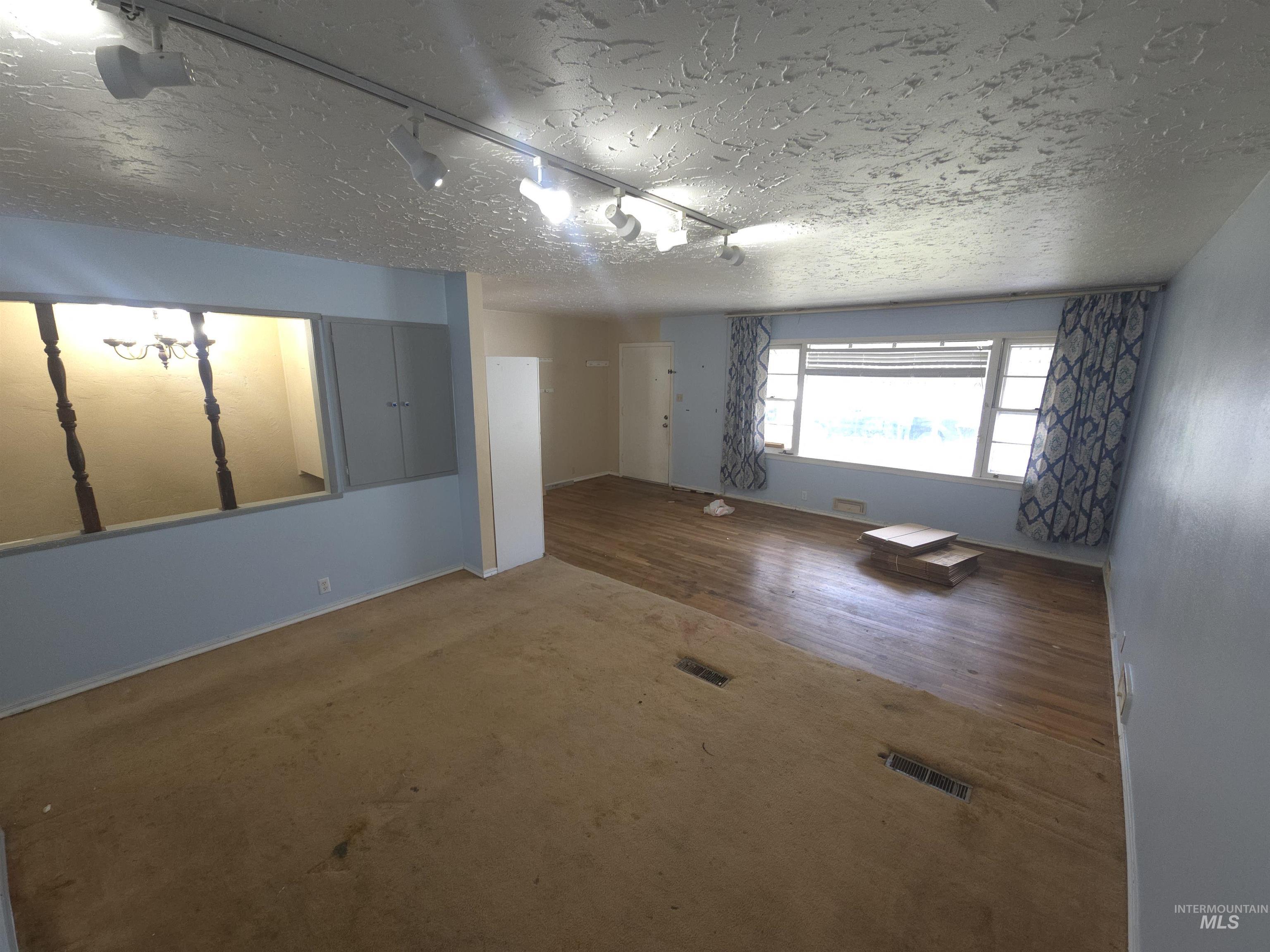 458 Rose Street North Twin Falls, ID 83301 - Photo 5 of 17 Unfurnished room featuring track lighting, a textured ceiling, and wood finished floors