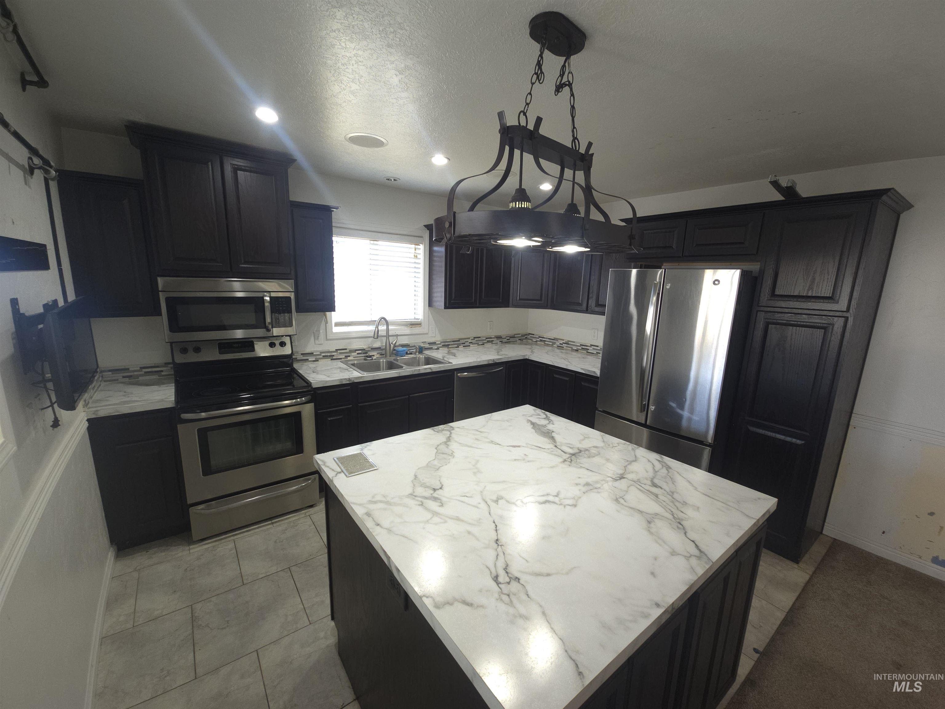 458 Rose Street North Twin Falls, ID 83301 - Photo 7 of 17 Kitchen with stainless steel appliances, pendant lighting, a center island, and dark cabinets