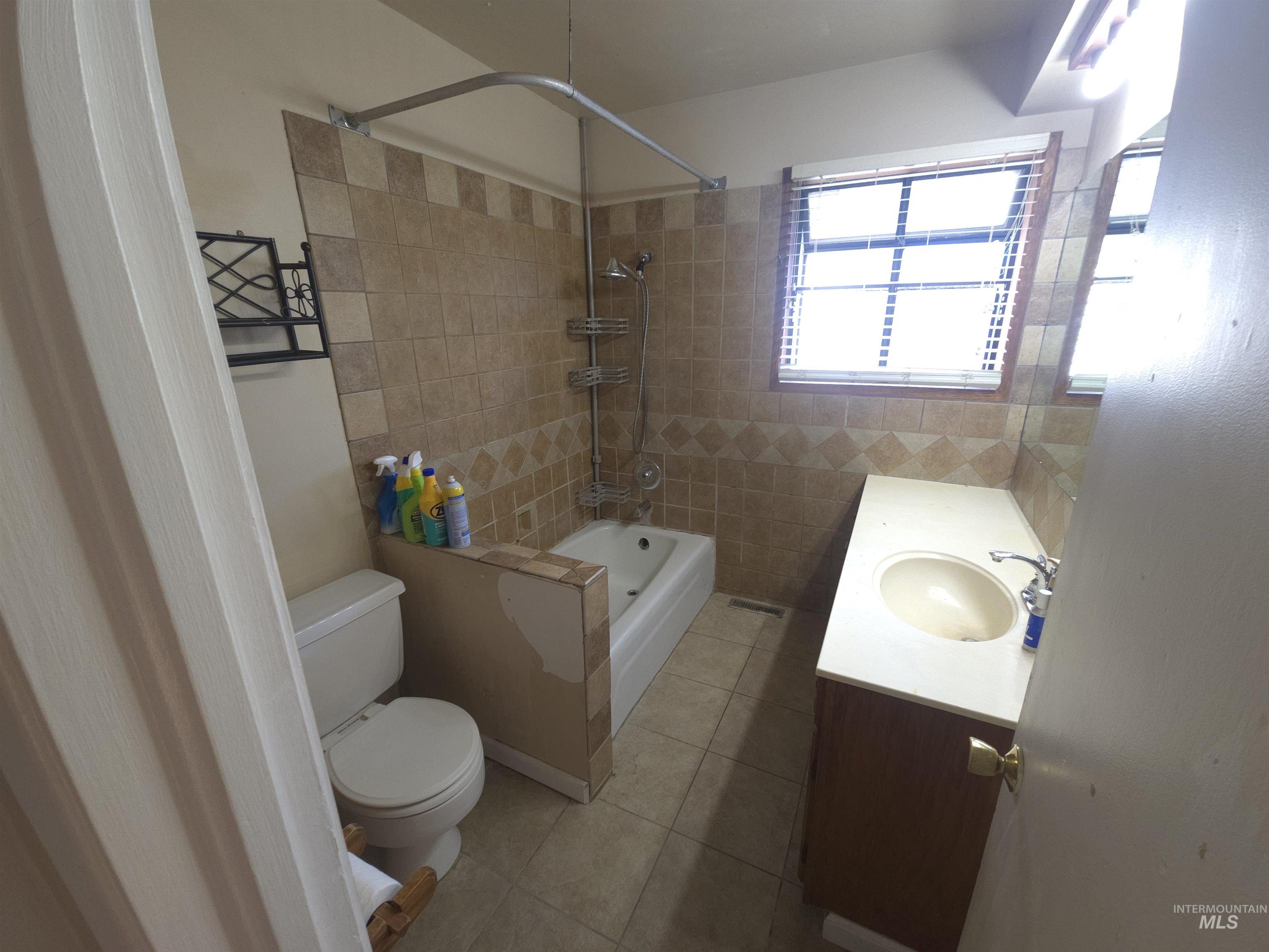 458 Rose Street North Twin Falls, ID 83301 - Photo 10 of 17 Bathroom featuring vanity, light tile patterned floors, shower / washtub combination, and tile walls
