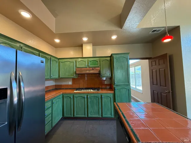 a kitchen with stainless steel appliances kitchen island granite countertop a refrigerator a sink and a stove