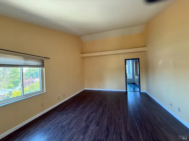 a view of an empty room with window and wooden floor