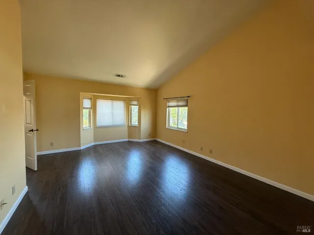 a view of an empty room with wooden floor and window