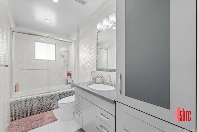 a bathroom with a sink vanity granite toilet and shower