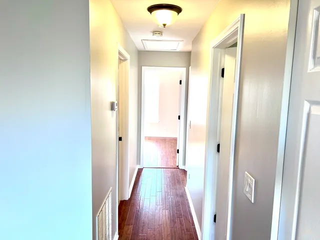 a view of a hallway with wooden floor and staircase