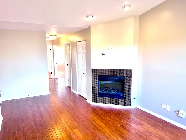 a view of an empty room with wooden floor and a fireplace