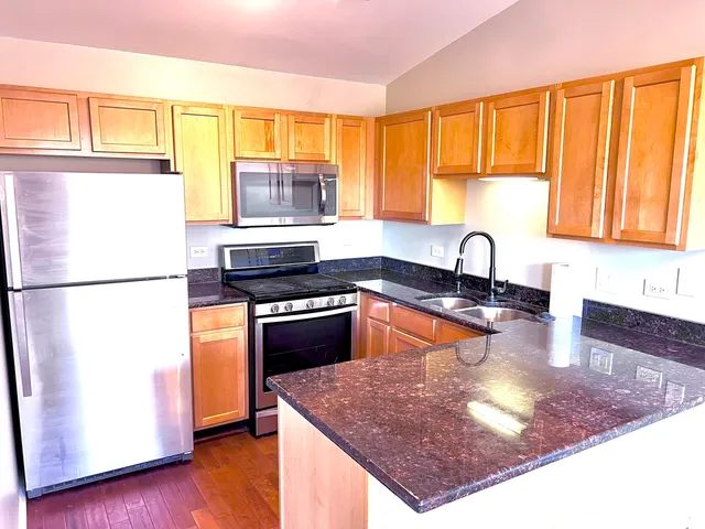 a kitchen with stainless steel appliances granite countertop a sink stove and refrigerator