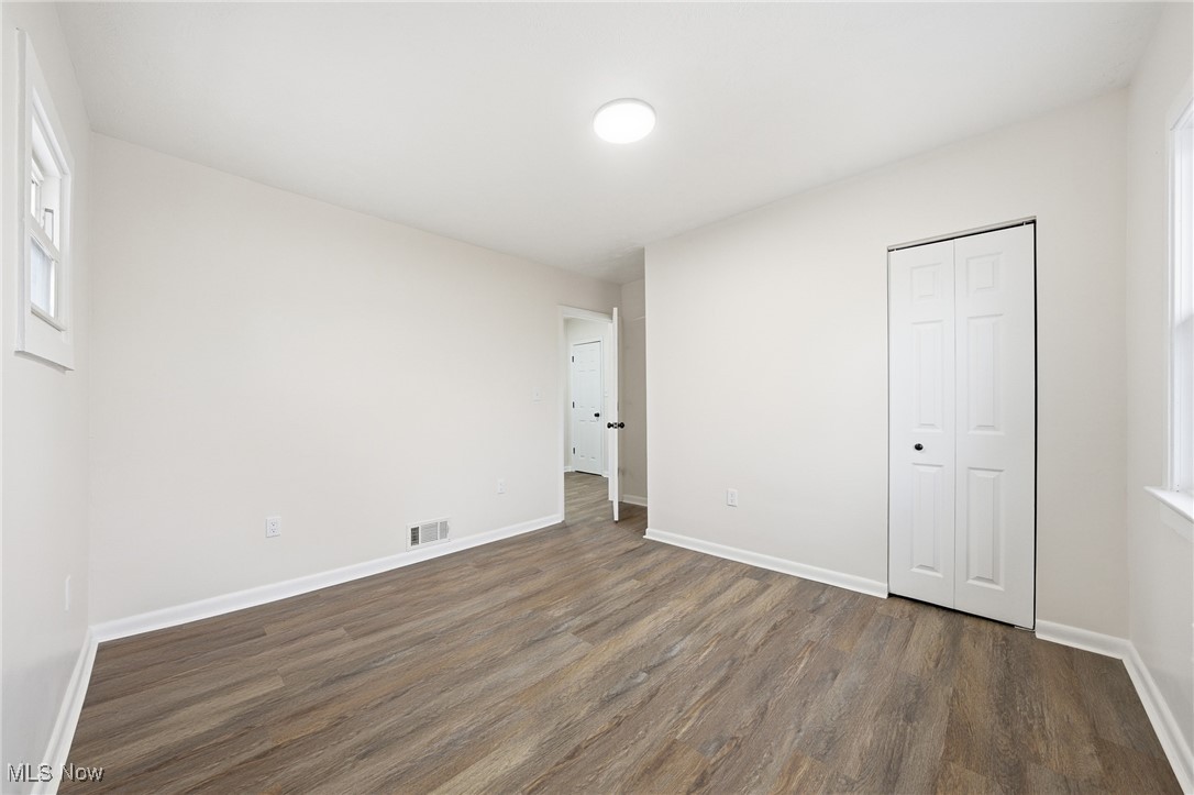 7911 Snow Road Parma, OH 44129 - Photo 25 of 44 Unfurnished bedroom featuring multiple windows, dark wood finished floors, and a closet