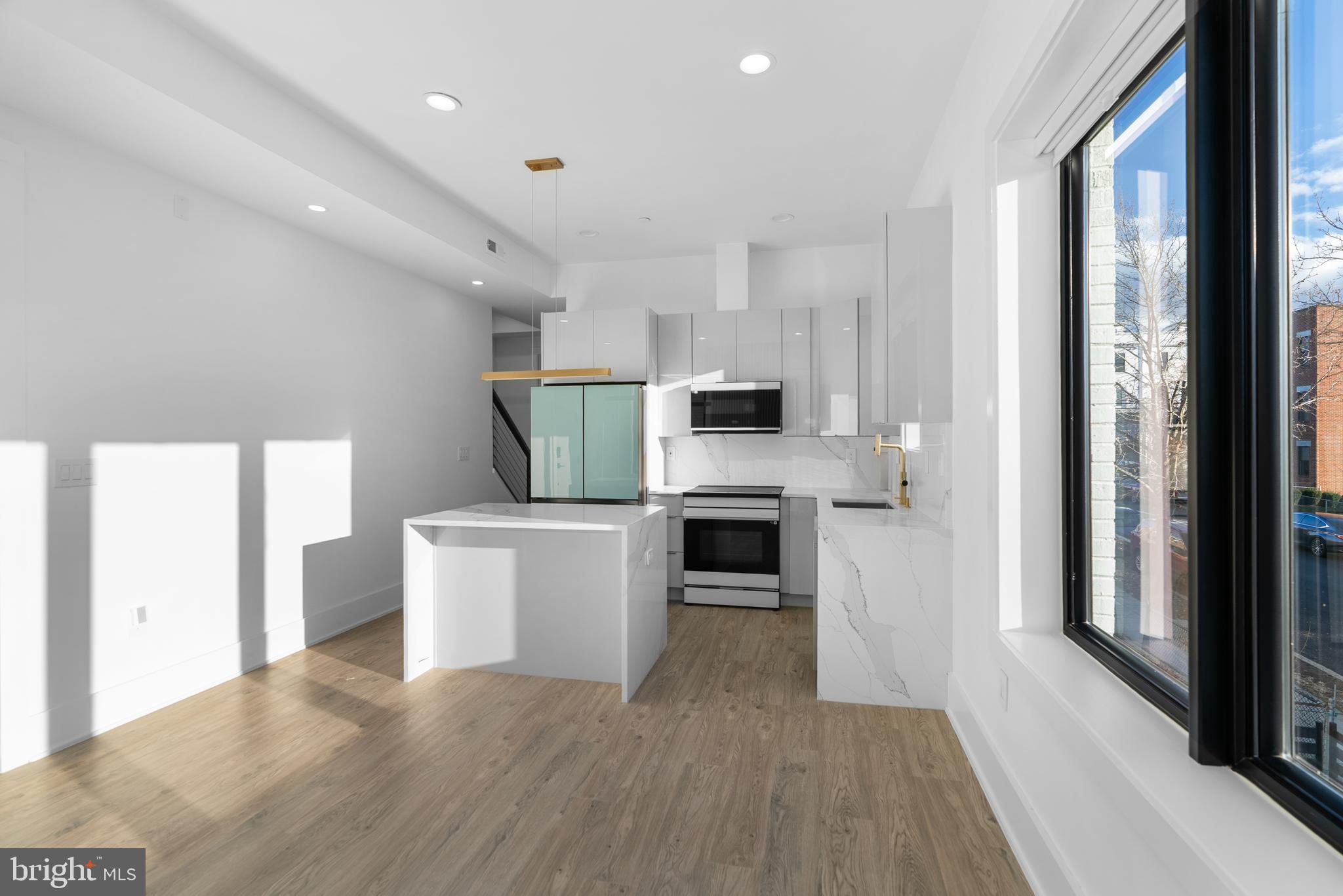 1140 Oates Street Northeast, Unit 202 Washington, DC 20002 - Photo 21 of 48 a kitchen with a refrigerator a stove top oven and white walls