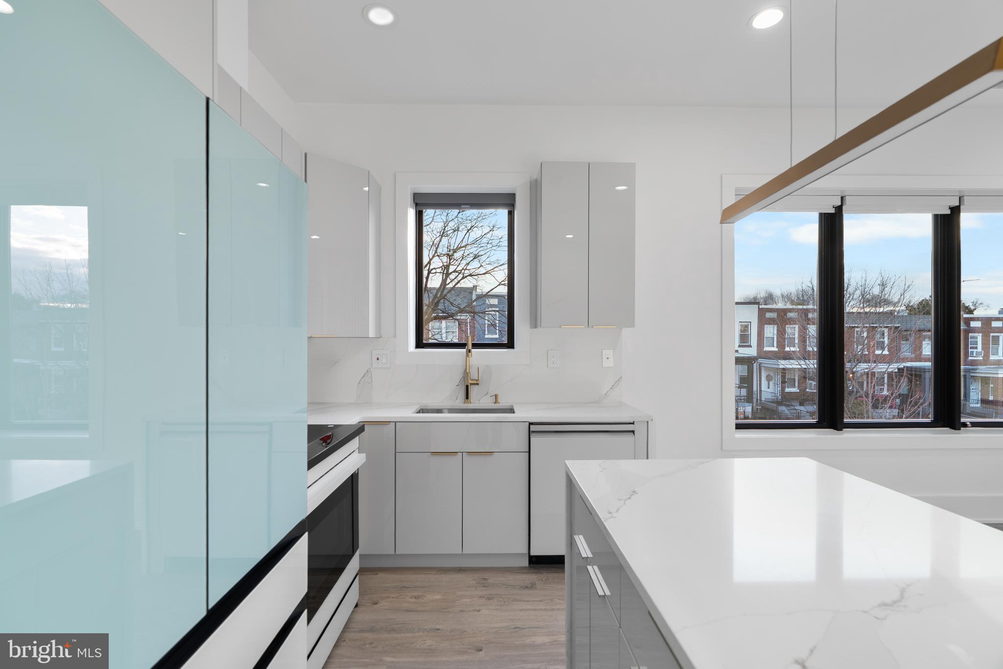 1140 Oates Street Northeast, Unit 202 Washington, DC 20002 - Photo 22 of 48 a large white kitchen with a sink a window and stainless steel appliances