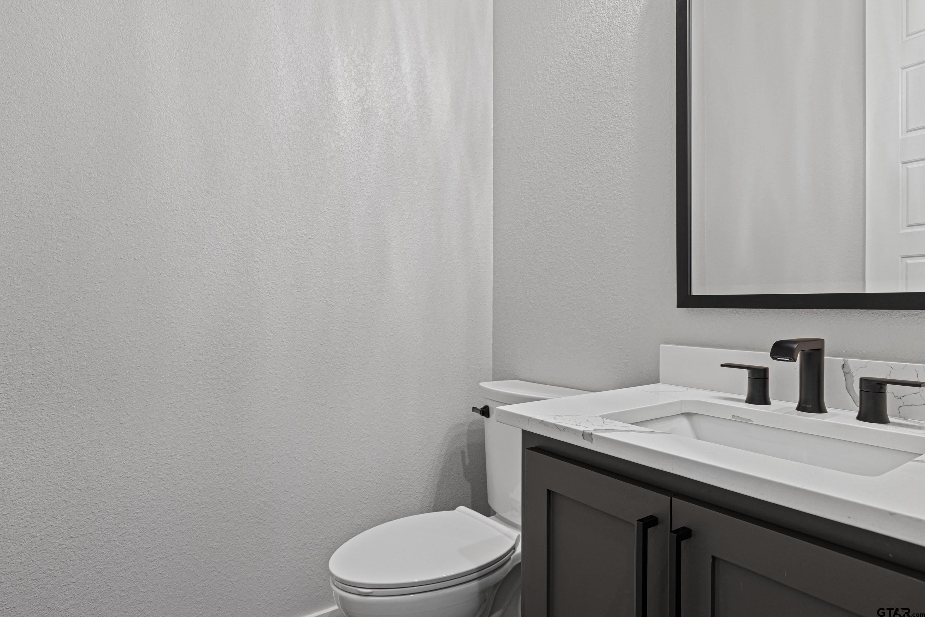 8947 Pomagranate Road Gilmer, TX 75645 - Photo 21 of 38 a bathroom with a granite countertop toilet sink and mirror