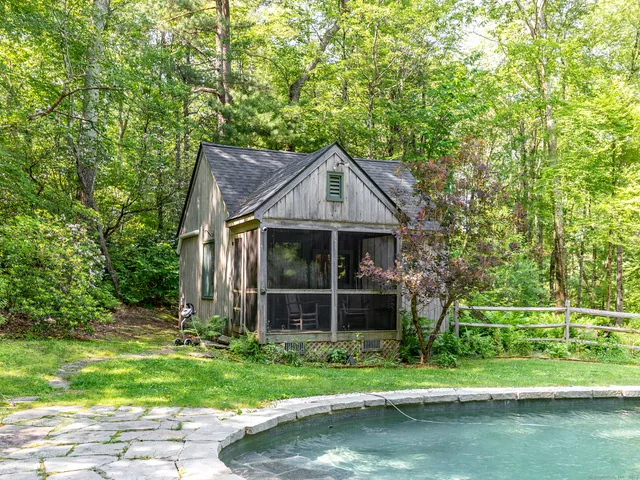 a view of pool with lawn chairs under an umbrella