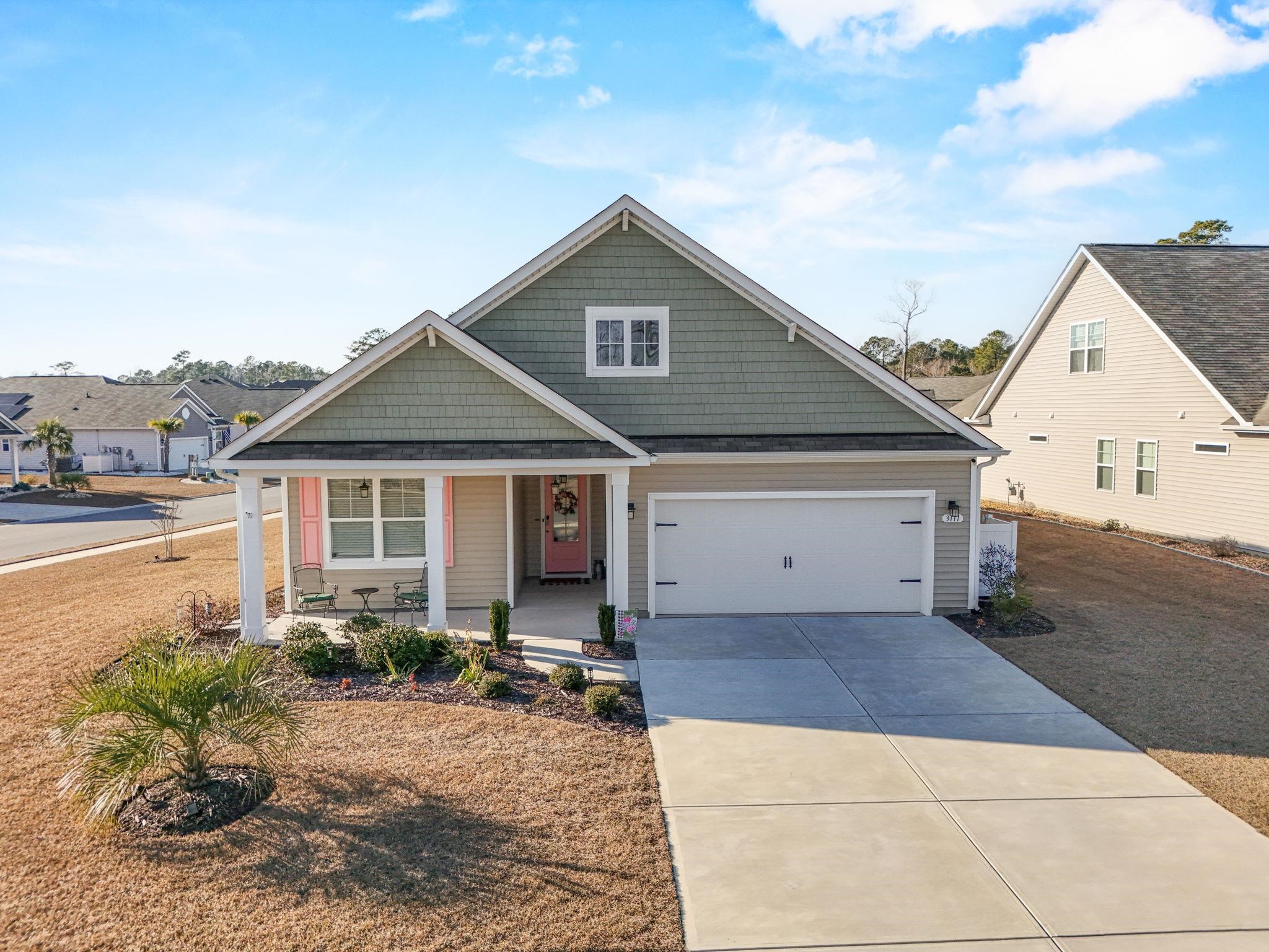 View of front facade featuring covered porch, driveway, and a garage