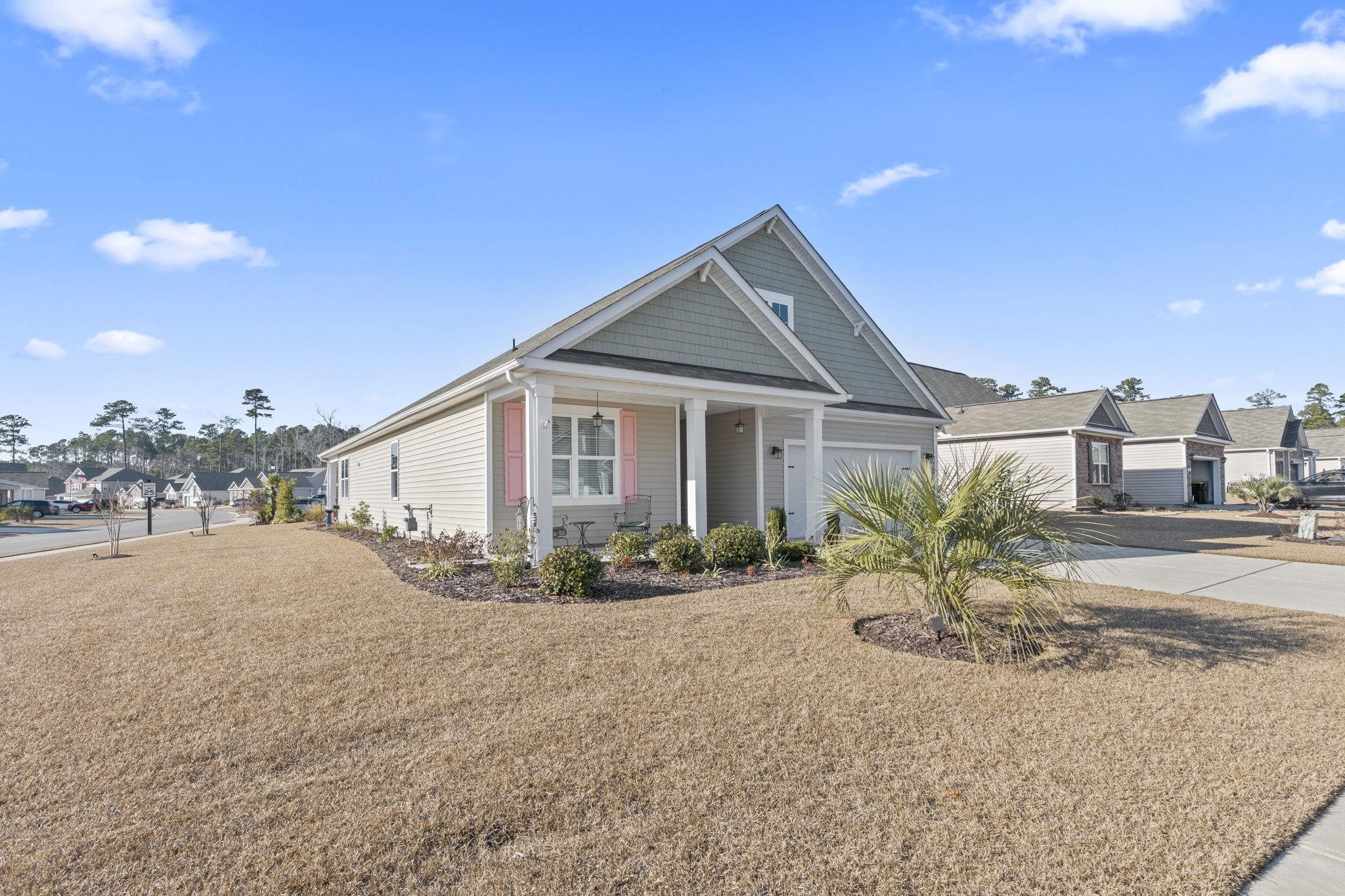 3111 Sutherland Drive Little River, SC 29566 - Photo 3 of 16 View of front of property featuring a residential view, a porch, a front lawn, driveway, and an attached garage