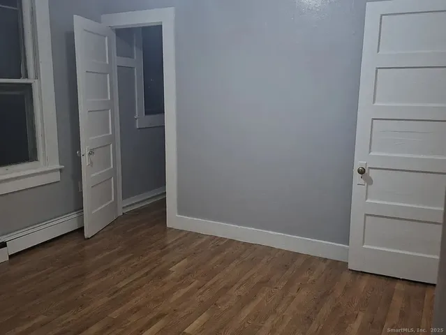 a view of an empty room with wooden floor and closet