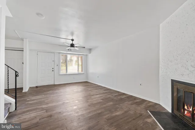 an empty room with wooden floor fireplace and windows