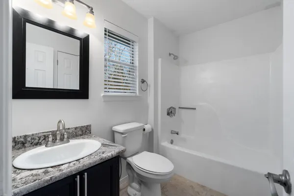 a bathroom with a granite countertop toilet a sink and a mirror