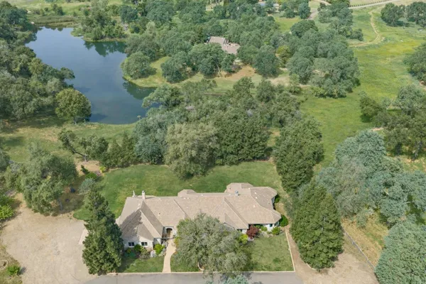 an aerial view of residential house with outdoor space and trees all around