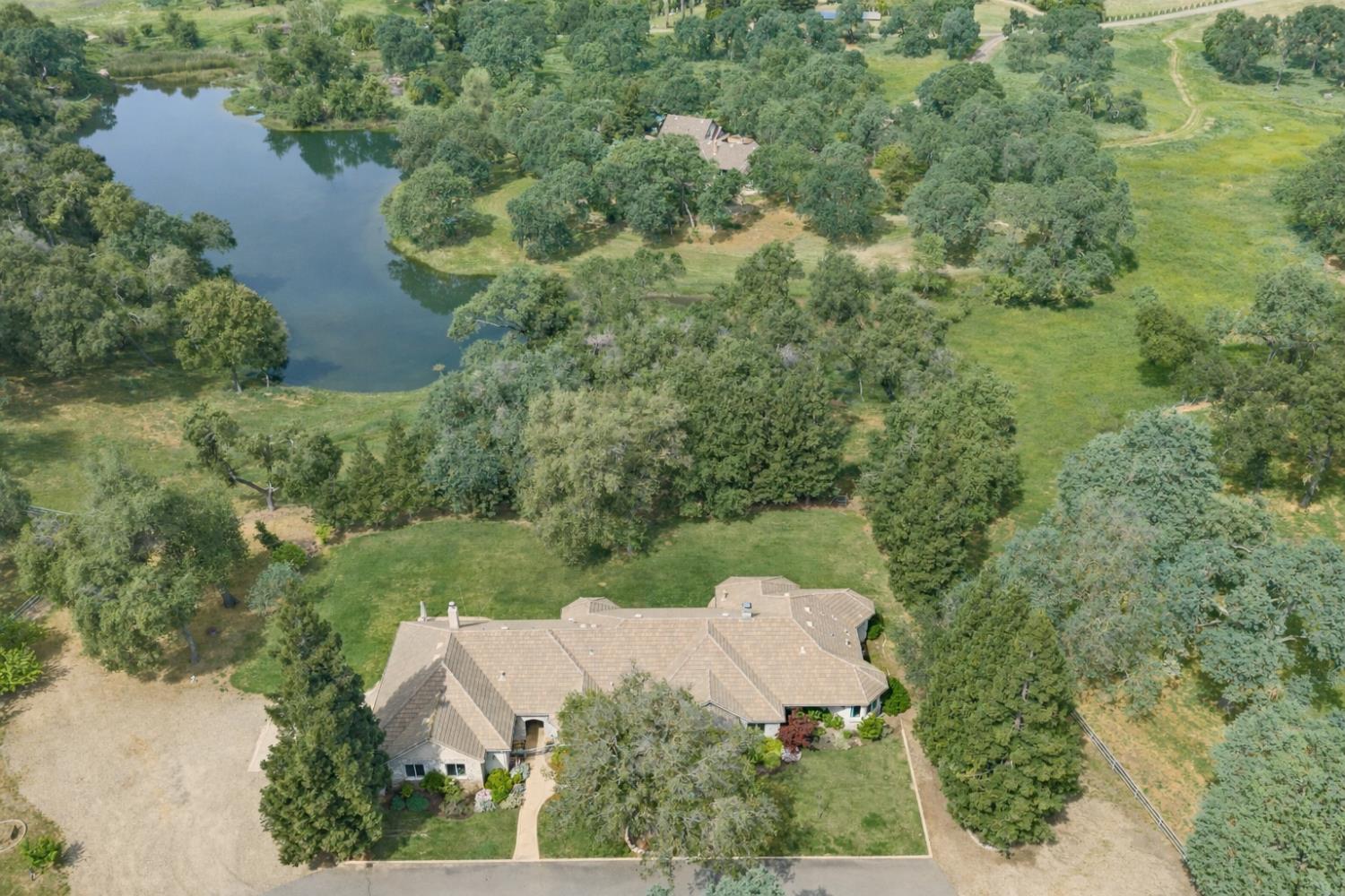 an aerial view of residential house with outdoor space and trees all around
