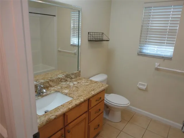 a bathroom with a granite countertop sink toilet and a mirror