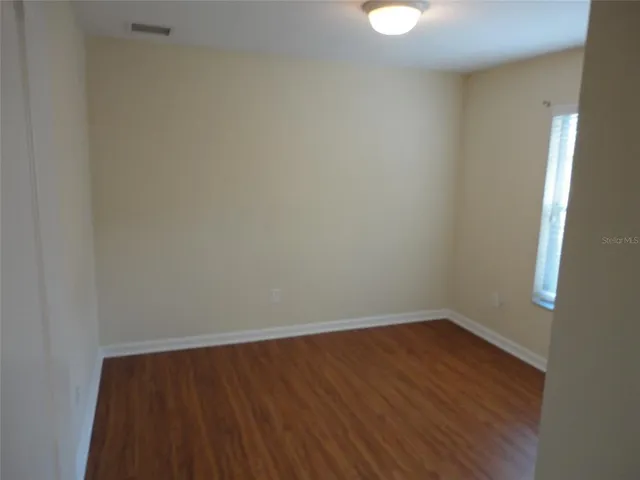 a view of an empty room with wooden floor and windows