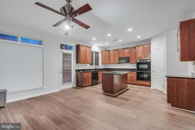 a large kitchen with stainless steel appliances kitchen island granite countertop a stove top oven a sink and dishwasher with wooden floor