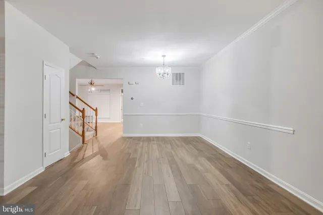 a view of an empty room with wooden floor and stairs