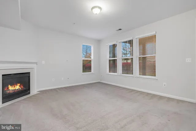 a view of an empty room with a window and fireplace