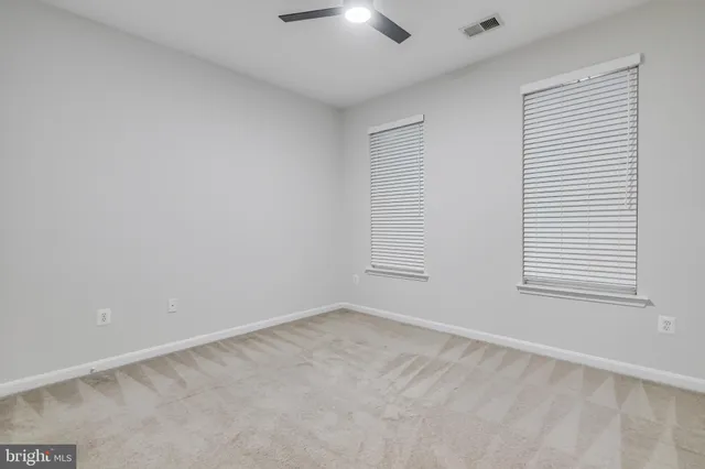 an empty room with a chandelier fan and windows