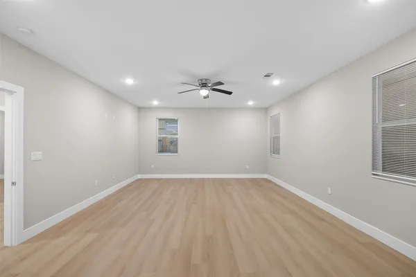 a view of an empty room with wooden floor and a window