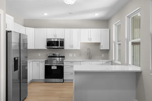 a kitchen with granite countertop a refrigerator and a stove top oven